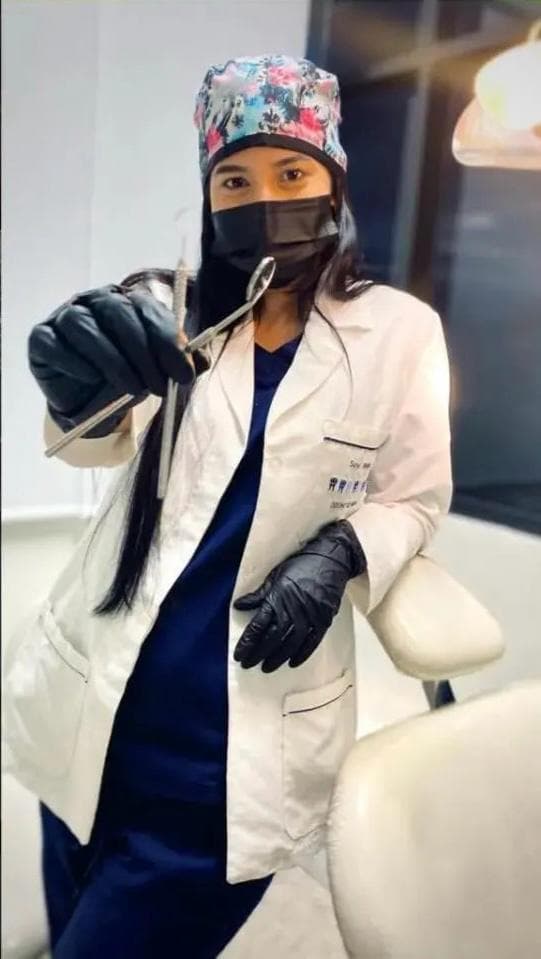 La Od. Sayl Molina, con bata y guantes, sostiene un espejo dental en su consultorio de Barinas